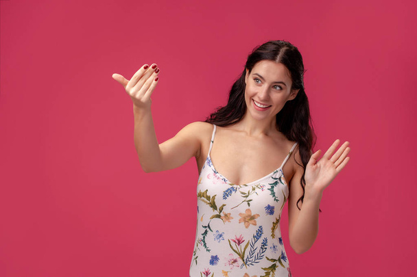 Portrait of a pretty young woman in a light dress standing on pink background in studio. People sincere emotions. - Foto, Imagen
