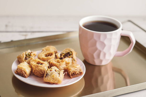 Rozmanité baklavy na malém talíři a šálku kávy podávané na kovovém pultu. Tradiční arabský dezert - Fotografie, Obrázek
