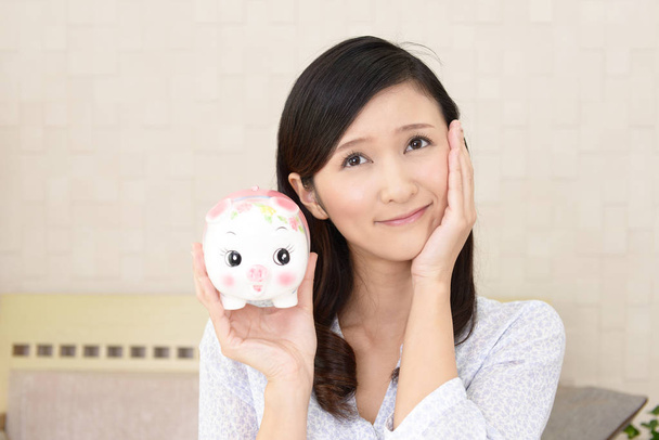 Asian young woman holding a piggy bank - Fotó, kép