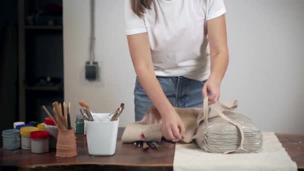 Mujer se está poniendo un delantal en su taller de artesanía, de pie cerca de la mesa
, - Imágenes, Vídeo