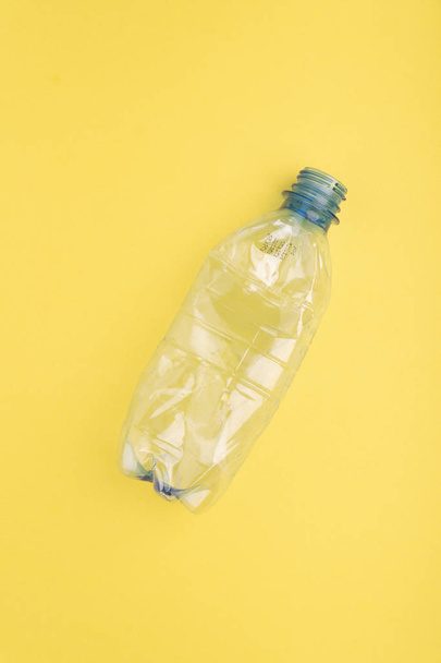 Crashed plastic bottle on yellow background. Plastic utilisation concept. Ecological problem, global environment. - Zdjęcie, obraz