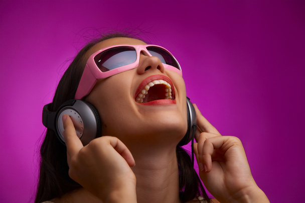 Glamour-Porträt einer jungen Brünetten mit pinkfarbener Sonnenbrille, die Musik hört - Foto, Bild