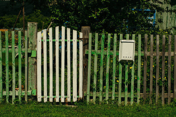 Egy régi fa zöld kerítés, egy kiskapuval, és egy postafiók. Rusztikus. Vidéki. - Fotó, kép
