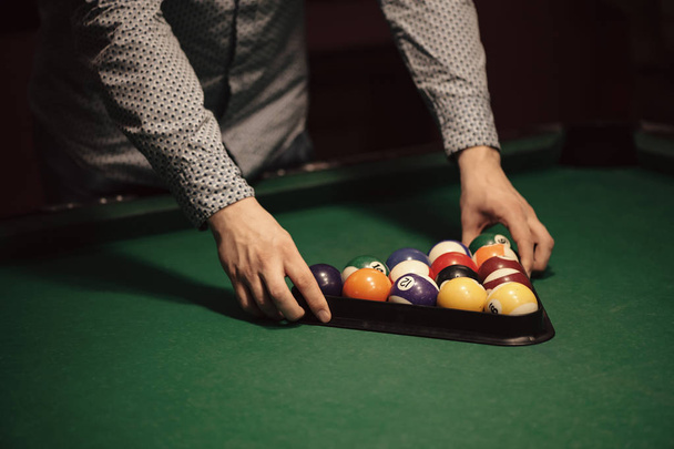 American billiard poule. Triangle of billiard balls. A man getting ready to start a game of billiards. - Photo, Image