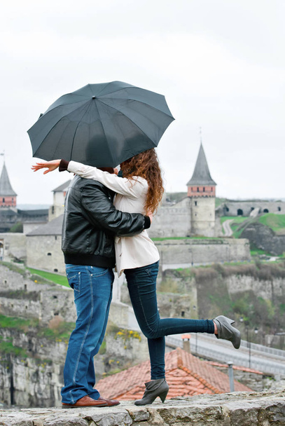 A couple hugging against the background of the fortress. Kiss under an umbrella. - Photo, Image