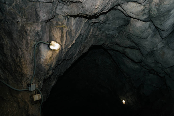 Nádherná jeskyně. Pohled z vnitřní temné kobky. Stěny jeskyně s texturou. Obraz podzemního tunelu. Vlhkost uvnitř jeskyně. Osvětlení vnitřní jeskyně pro výlety. - Fotografie, Obrázek
