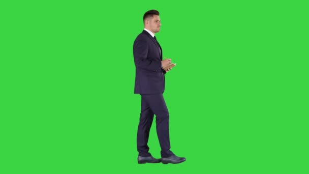 Fiatal pozitív kaukázusi üzletember gyalogos és így ellenőrzőlista egy zöld képernyő, chroma key. - Felvétel, videó