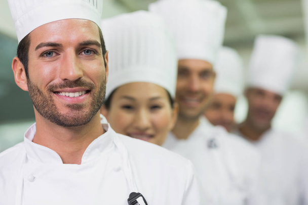 Happy team of chefs standing in line in a commercial kitchen - Fotó, kép