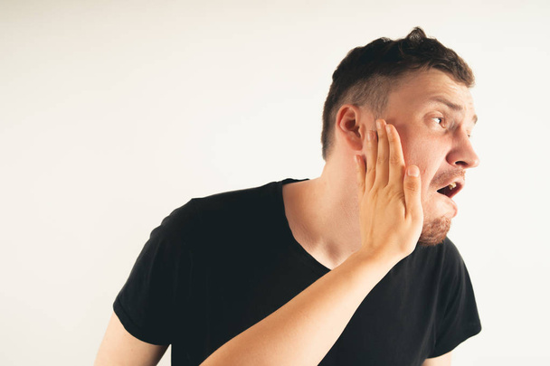 Crop person slapping scared man in faceEmotional male getting slapped in face while shouting with closed eyes in fear on white background - Фото, изображение