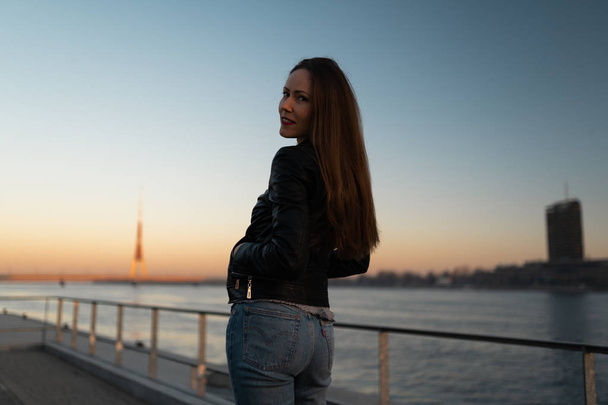 Jeune femme confiante lors d'une promenade de style de vie le long de la rivière Daugava au coucher du soleil
 - Photo, image