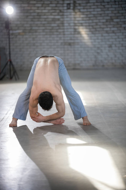 An athletic man on capoeira training. Bending down. Spine stretching - Photo, image
