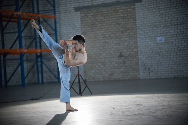 Um atlético em treino de capoeira. Executa o pontapé no ar
 - Foto, Imagem