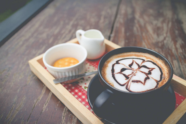Gorąca kawa z pianki mleka sztuki. Czarna filiżanka kawy. Gorąca kawa i - Zdjęcie, obraz
