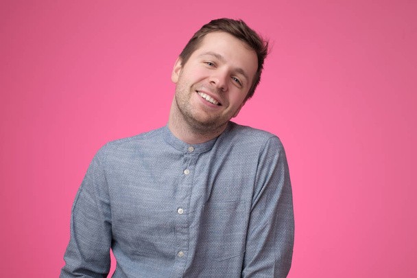 Pohledný mladý muž smějící se na růžovém pozadí - Fotografie, Obrázek