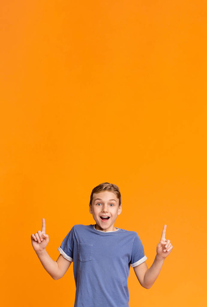 erstaunt lächelnder Teenie-Junge zeigt mit zwei Fingern auf leeren Raum - Foto, Bild