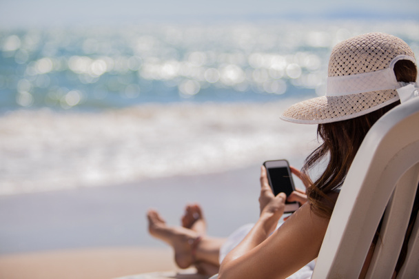 mladá žena s mobilním telefonem na pláži - Fotografie, Obrázek