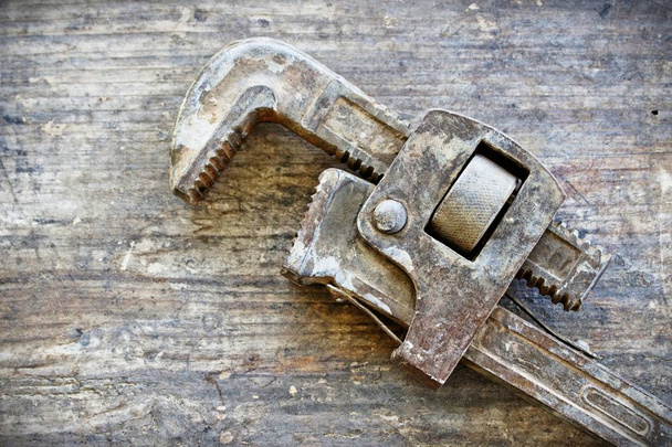 An old rustic pipe plumbing wrench lying on an old wood plank - Photo, image