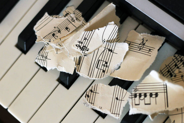 Σκισμένες μουσικές νότες, κομμάτια χαρτιού στο πιάνο - Φωτογραφία, εικόνα