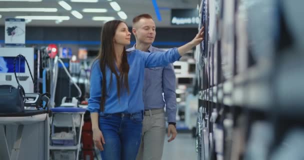 Un uomo e una donna aprono la porta della lavatrice ispezionare il design e la qualità prima di acquistare nel negozio
 - Filmati, video