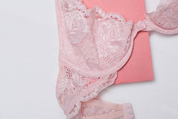 Pink Lace lijfje en Kladblok op witte achtergrond. Modieus concept. Close-up - Foto, afbeelding