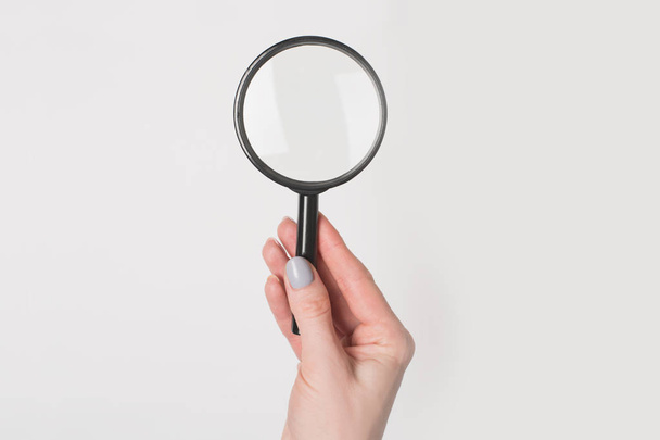 Female hand holding magnifier isolate on light background. - Фото, зображення