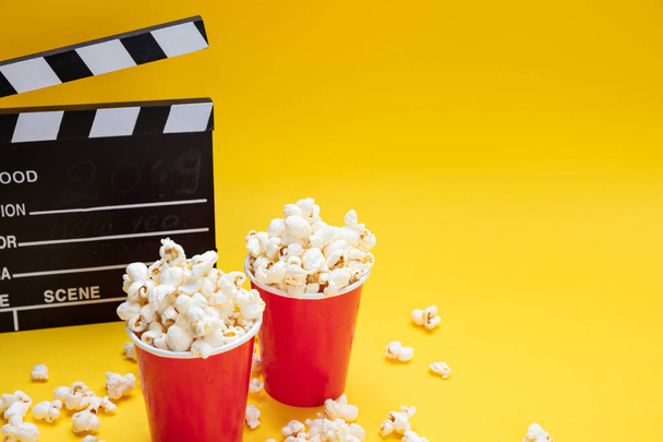 Clapperboard and pop corn on yellow color background - Foto, Imagen