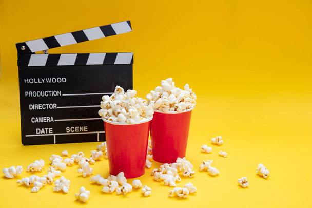 Klappbrett und Popcorn auf gelbem Hintergrund - Foto, Bild