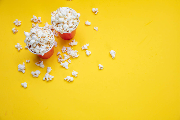 Popcorn in roten Pappbechern auf gelbem Hintergrund - Foto, Bild