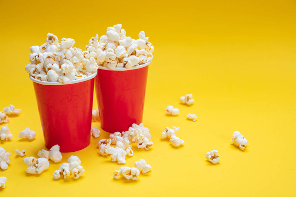 Pop corn in red paper cups on yellow color background - Photo, Image