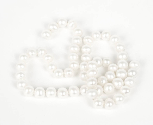Pearl necklace laid out over white background - Φωτογραφία, εικόνα