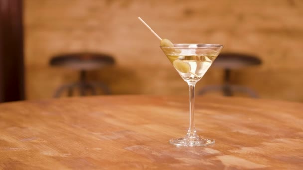 Tiro de paralaxe de um copo de martini em uma mesa de madeira vazia
 - Filmagem, Vídeo