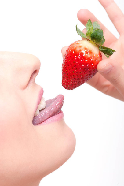 close-up womans lips and a strawberry isolated on white background - 写真・画像