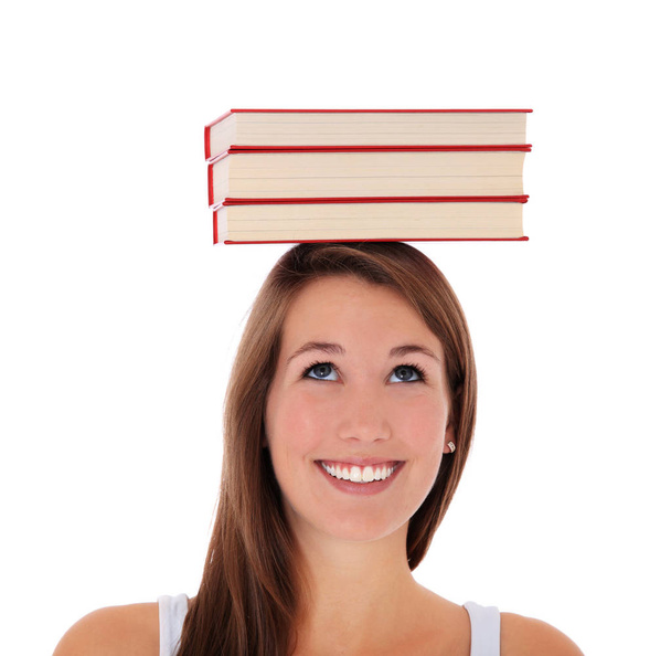 Aantrekkelijke jonge vrouw balanceren boeken op haar hoofd. Alles op witte achtergrond. - Foto, afbeelding