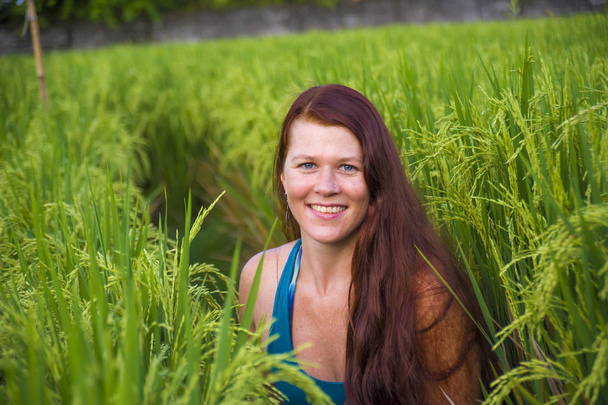 mladý šťastný a krásný zrzavé vlasy žena usmívající hravý baví pózování uvolněný izolovaný na zelené rýžové pole v Asii turistické výlety a letní prázdniny cestování - Fotografie, Obrázek