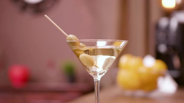 Zbliżenie paralaksy strzał Martini kieliszek z oliwek - Materiał filmowy, wideo