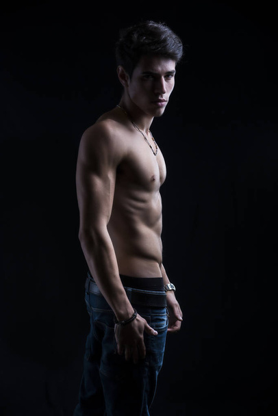Handsome muscular shirtless young man standing confident, profile view, looking at camera - Photo, image