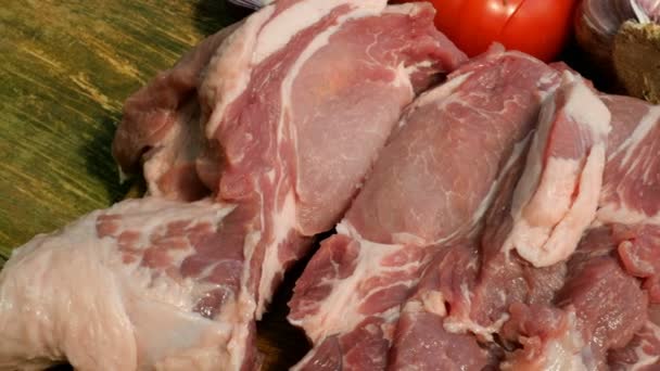 Çiğ et biftek ahşap bir kesme tahtası üzerinde domuz eti veya sığır eti büyük bir parça kesilir. Sebzeler: domates, tatlı biber, sarımsak. Close. - Video, Çekim