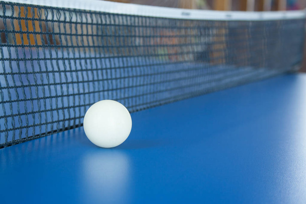 fehér labda asztalitenisz fekszik egy kék asztalon - Fotó, kép