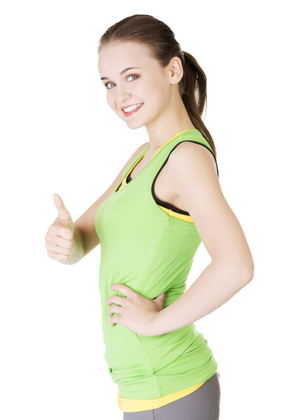 Fitness woman in sport clothes gesturing thumbs up - Foto, Bild