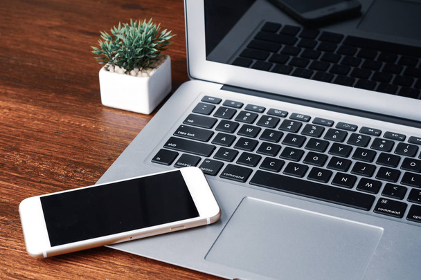 Laptop and phone with black screen on wooden desk. - Fotografie, Obrázek