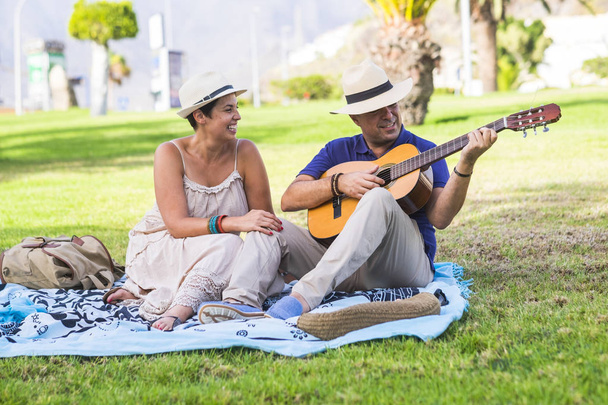 casal relaxante no parque, enquanto o homem tocando na guitarra
 - Foto, Imagem