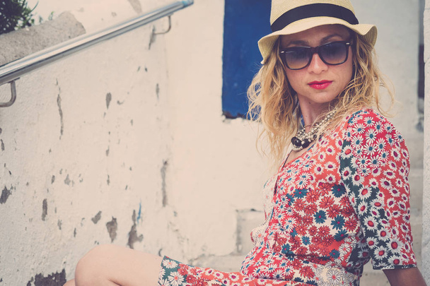 Schöne junge kaukasische Frau im modischen Stil farbigen Kleid posieren und entspannen - Sommer-Stil mit Sonnenbrille und Hut für trendige Menschen im Freien - Foto, Bild