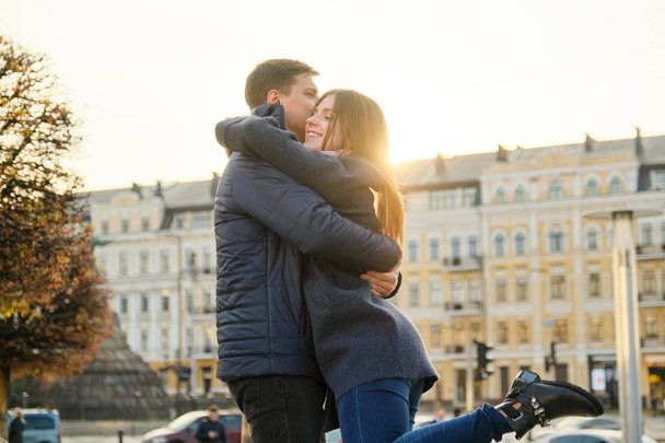 Young beautiful couple is embracing and having fun, romance in the spring city, golden hour - Foto, Imagem