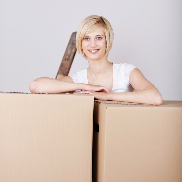smiling woman leaning on cardboard boxes - Fotó, kép