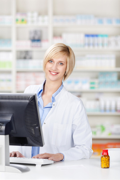 Pharmacist Using Computer At Pharmacy Counter - Valokuva, kuva