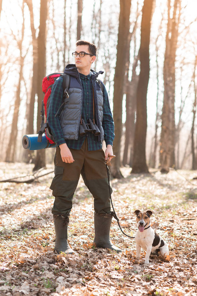 Młody człowiek z plecakiem, lornetką i psem - Zdjęcie, obraz