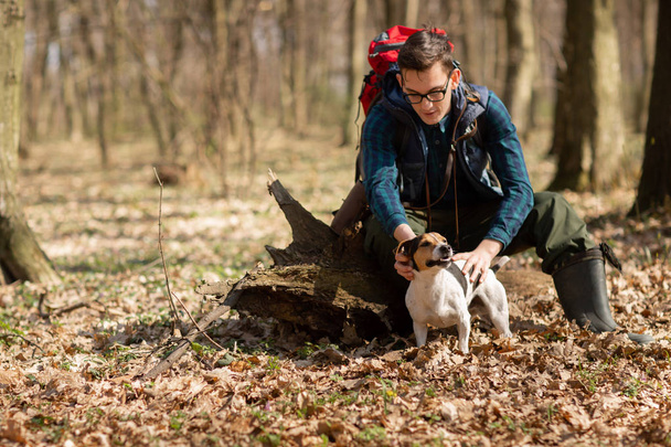 Młody człowiek z plecakiem wędrujący z psem po lesie. Pojęcie natury i ćwiczeń fizycznych - Zdjęcie, obraz