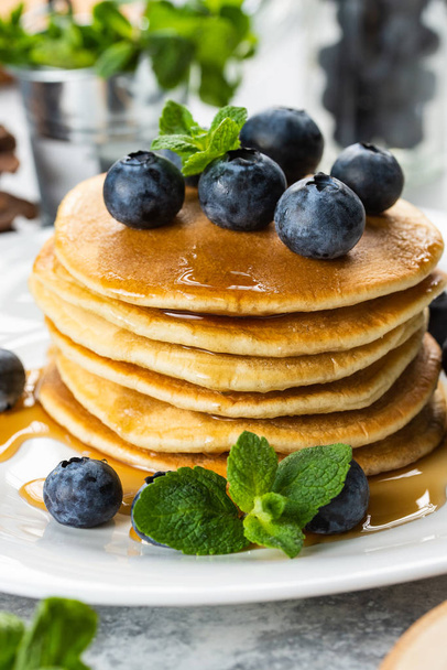 Homemade pancakes with fresh blueberries, maple syrup and mint stacked on plate - Fotografie, Obrázek