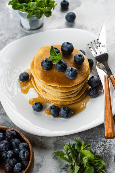 Homemade pancakes with fresh blueberries, maple syrup and mint stacked on plate - Valokuva, kuva