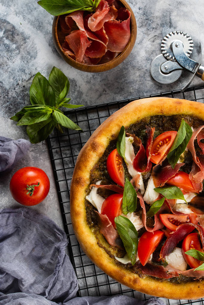 Gebakken pizza met ham en groenten op grijs marmeren tafelblad met ingrediënten - Foto, afbeelding